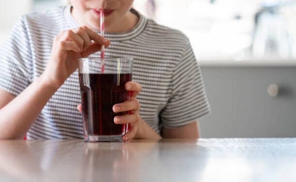 Close Up Of Girl Drinking Sugary Fizzy Soda From Glass With Straw